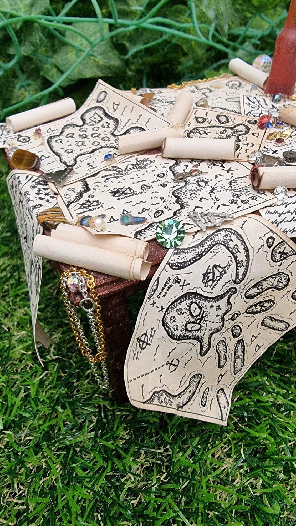 1:12 scale dollshouse brown table scattered with pirate treasure maps, bottle of rum and treasure, including jewels and chains