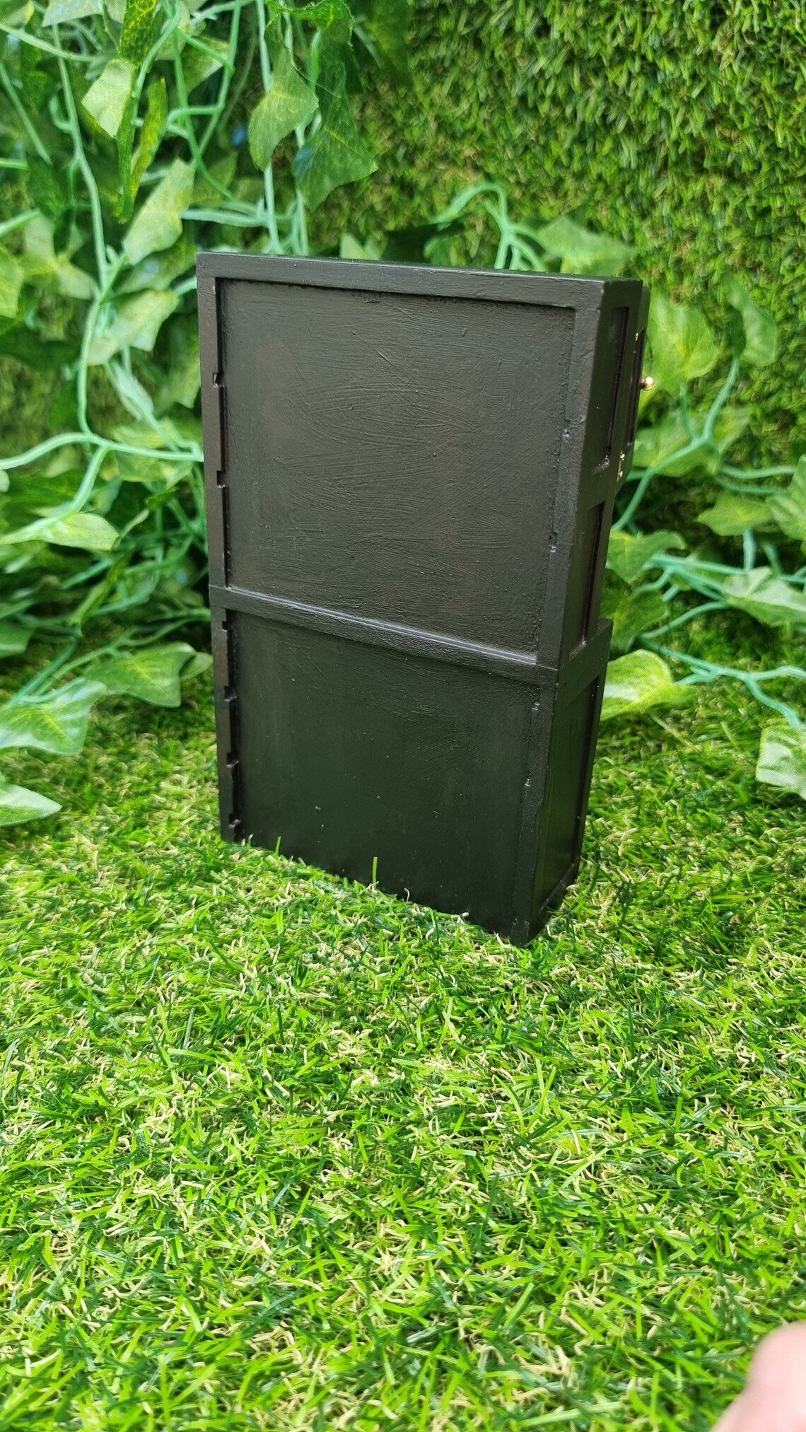 Back view of a black 1:12 scale dresser against a green background