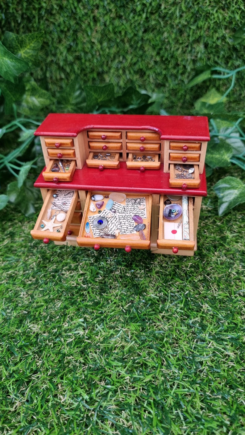 1:12 scale desk with 21 drawers has 7 open drawers. Each drawer is filled with different items, including maps, parchments, shells, starfish, letter, trinkets and curios