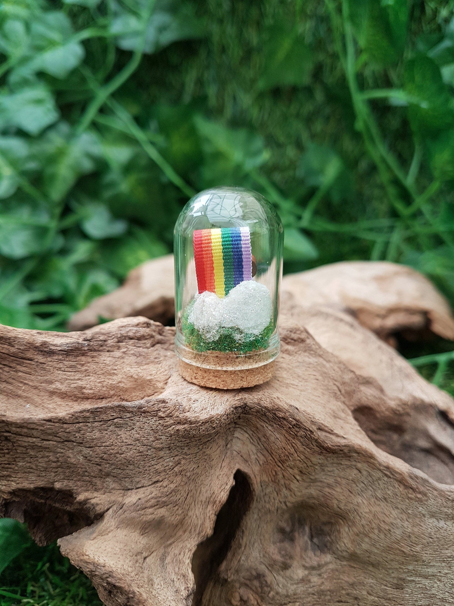 View showing the back ofnthe miniature glass bell jar containing a curl of rainbow ribbon with miniature cloud at end of the ribbon at the back