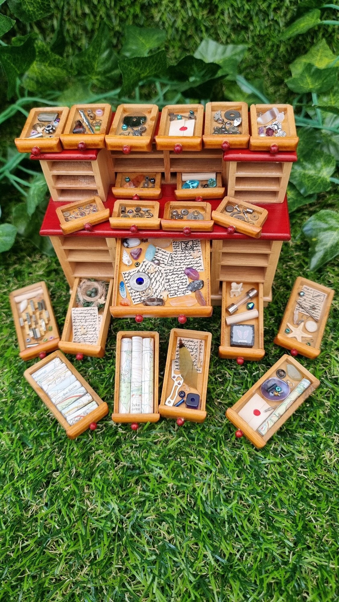 1:12 scale desk with 21 drawers has all drawers removed and on display. Each drawer is filled with different items, including maps, parchments, shell down, butterfly box, starfish, letters, quill, gemstones, nest, trinkets and curios