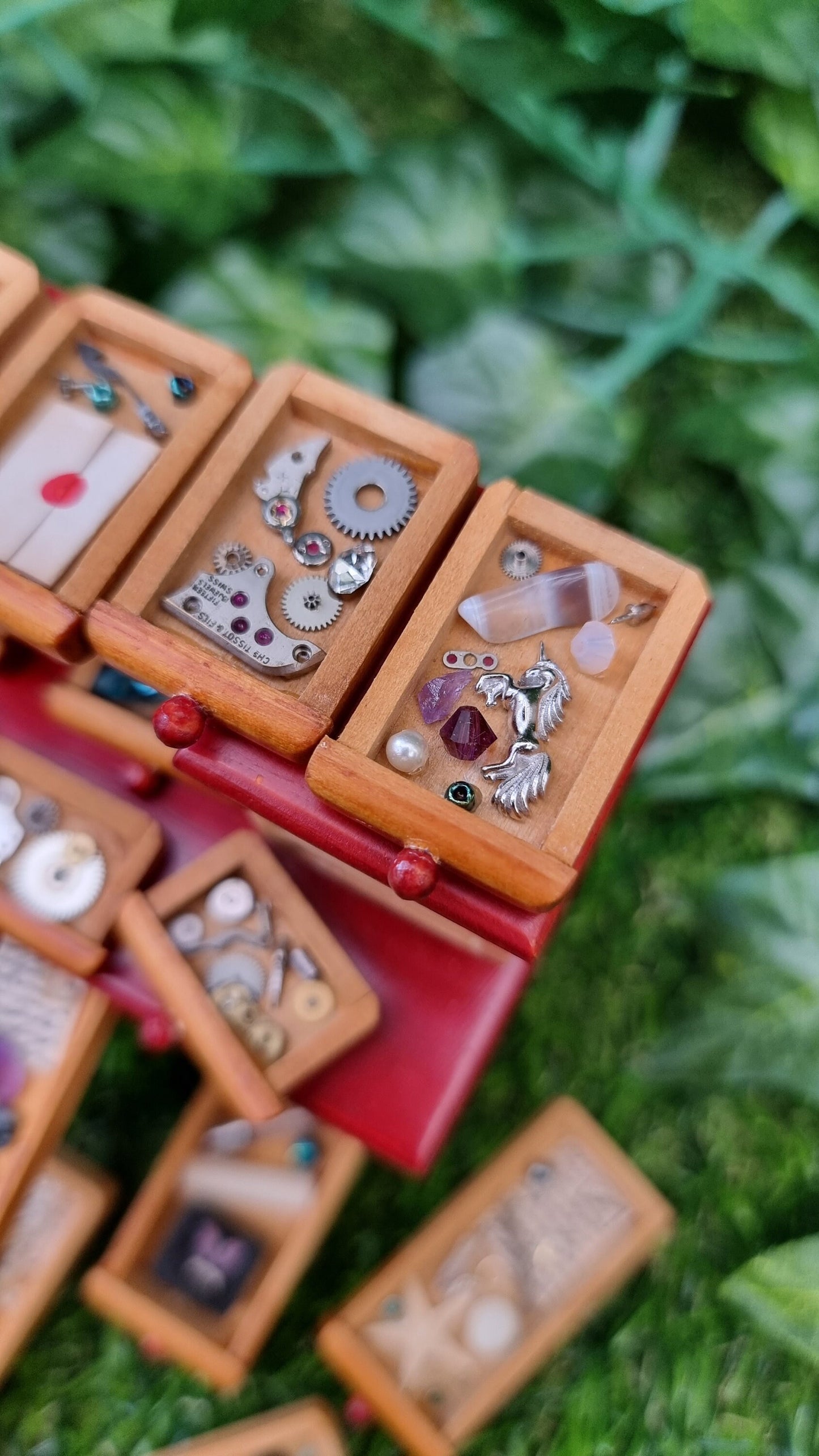 Detail of a 1:12 scale desk with 21 drawers has all drawers removed and on display. Each drawer is filled with different items, including parchments, shells, letters, quill, silver unicorn, gemstones, nest, trinkets and curios