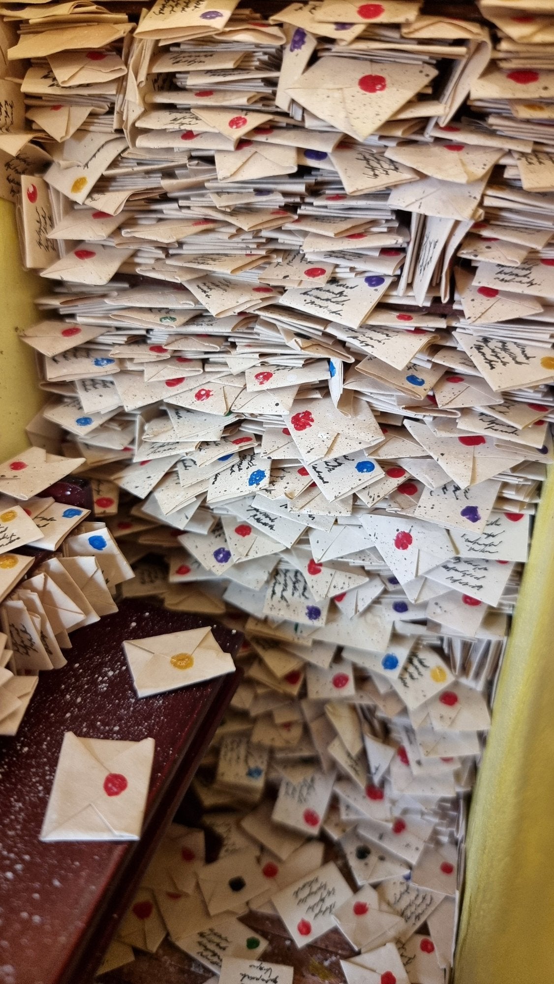 Hundreds of 1:12 scale letters are crammed into shelves above a desk crammed with more letters 