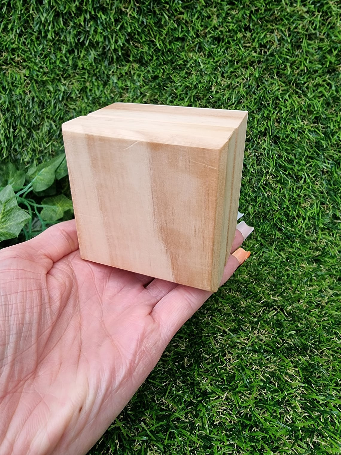 A hand holds a closed small brown wooden box