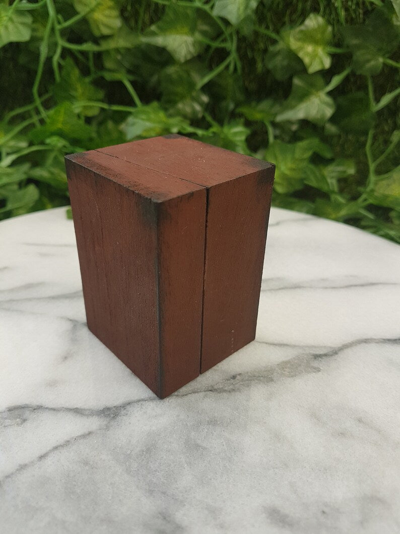 A 1:12 scale miniature brown apothecary cabinet is shown closed open on a marble slab