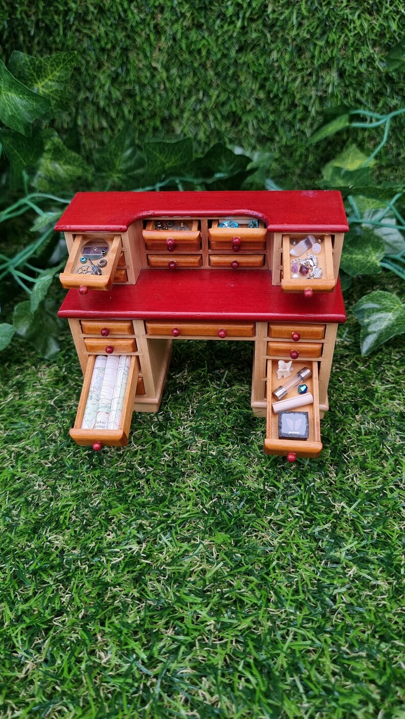 1:12 scale desk with 21 drawers has  6 open drawers. Each drawer is filled with different items, including maps, parchments, bones, glass tube, butterfly box, gemstones, nest, trinkets and curios