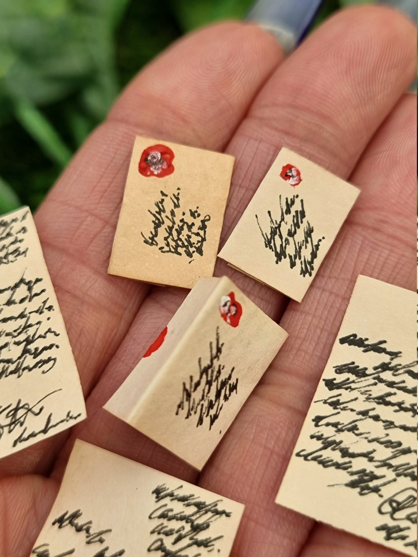 6 1: 12 scale miniature aged letters are displayed in the open palm of a hand. The photo shows the detail of 2 sealed letters with address and stamps. The other letters are fully written and one is open showing a red seal. 