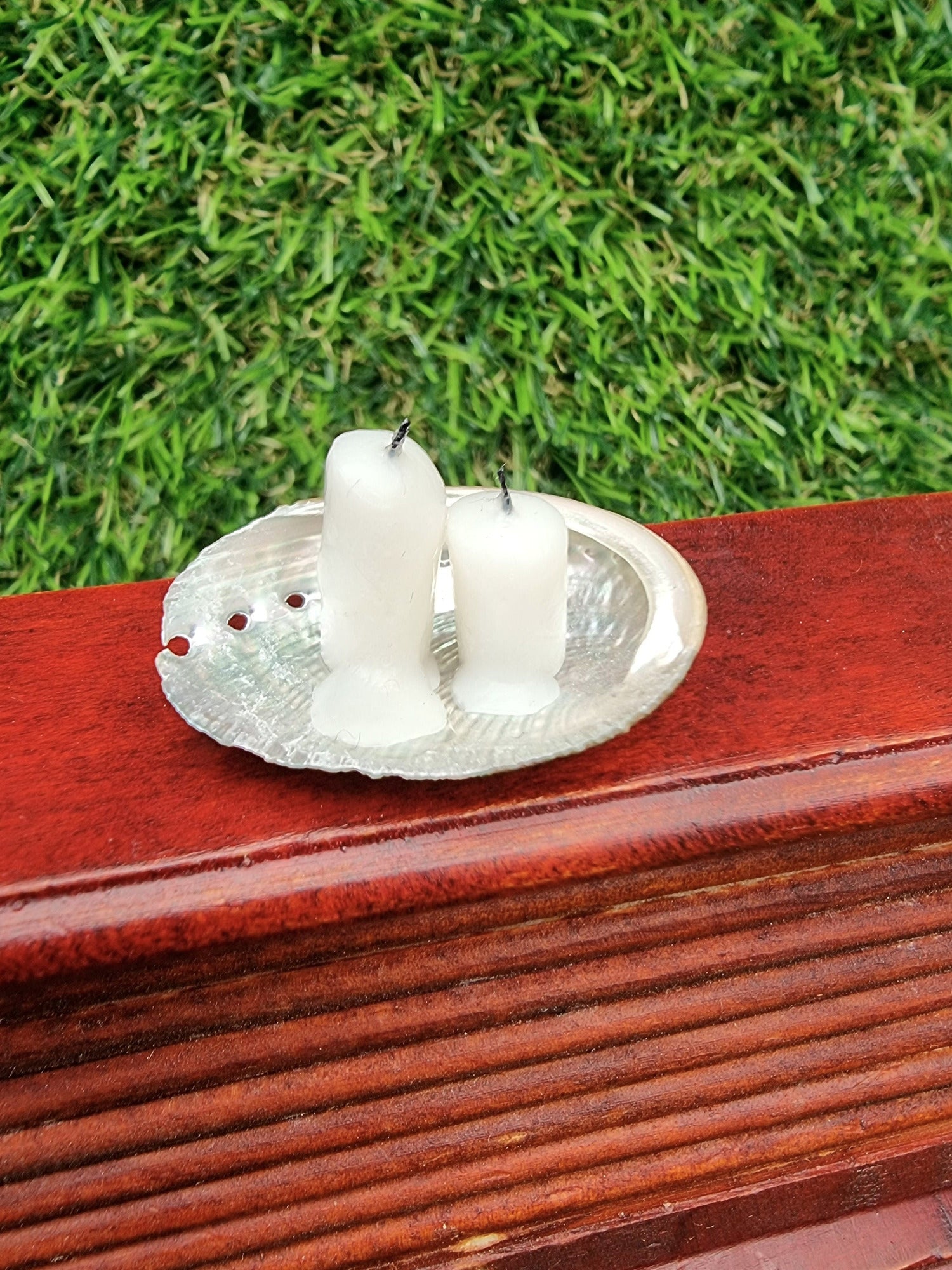 Two white 1:12 miniature candles in a small abalone shell dish, displayed on a miniature desk